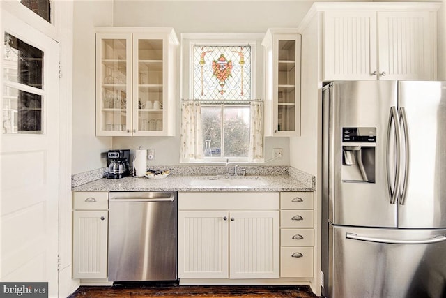 kitchen featuring stainless steel appliances, light stone countertops, sink, and white cabinets