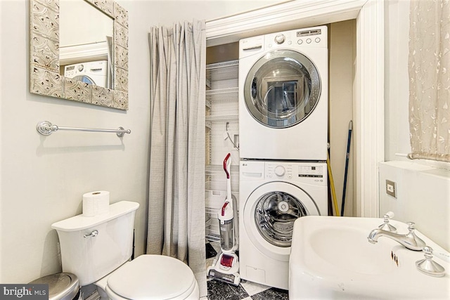 bathroom with sink, toilet, and stacked washer / dryer