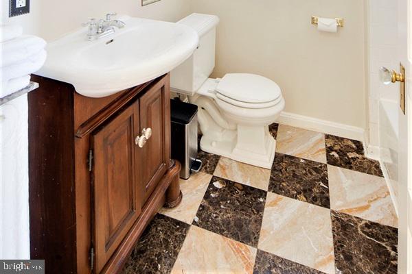 bathroom featuring vanity, a bath, and toilet