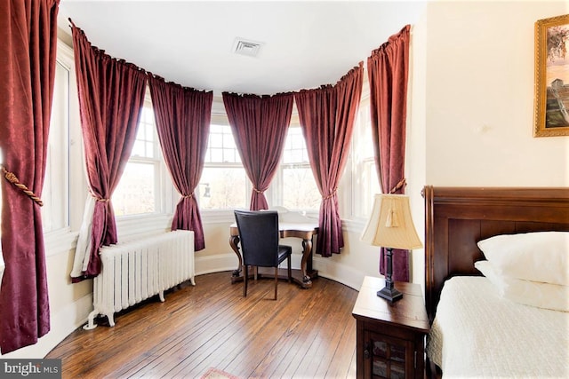 bedroom featuring radiator heating unit and dark hardwood / wood-style flooring