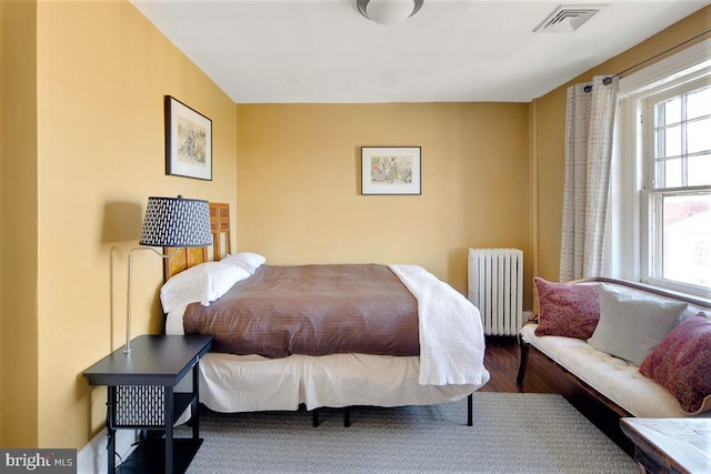 bedroom featuring radiator heating unit and wood-type flooring