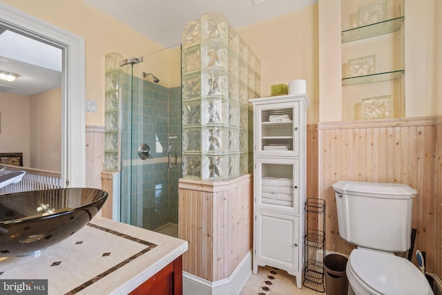 bathroom with a tile shower, vanity, toilet, and wood walls