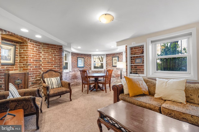 carpeted living room featuring brick wall