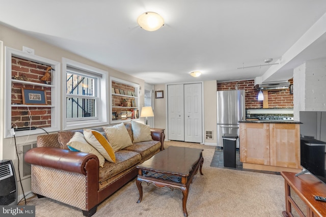 carpeted living room with heating unit, built in shelves, and brick wall