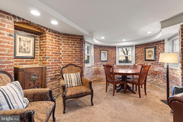 carpeted dining space with brick wall