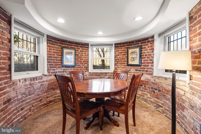 dining room featuring carpet flooring and brick wall