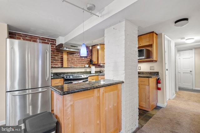 kitchen with appliances with stainless steel finishes, dark stone countertops, hanging light fixtures, brick wall, and dark carpet