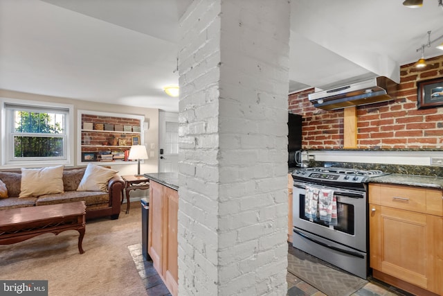 kitchen featuring dark stone countertops, electric range, carpet flooring, brick wall, and light brown cabinets