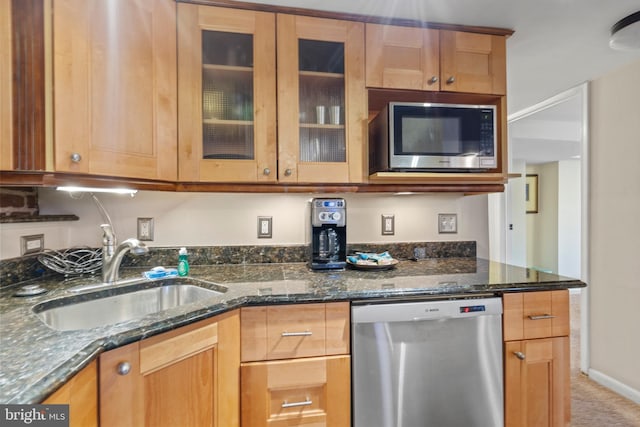 kitchen featuring appliances with stainless steel finishes, sink, and dark stone countertops