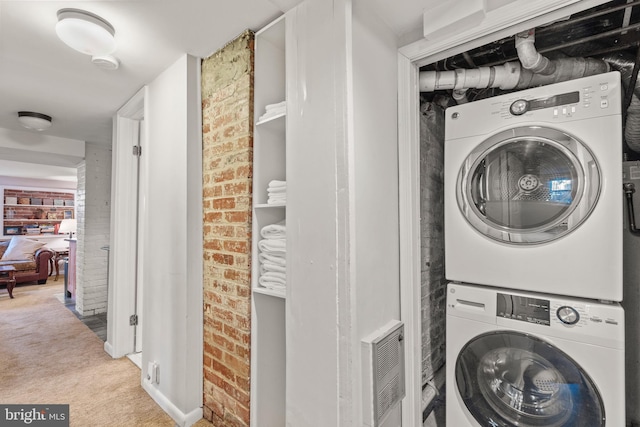 washroom with stacked washer and dryer, brick wall, and carpet