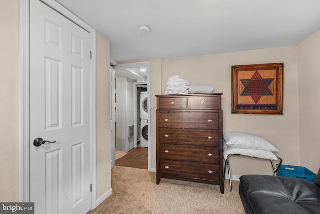 sitting room featuring light carpet and stacked washer and clothes dryer