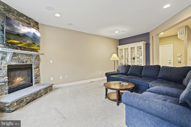 carpeted living room with a stone fireplace