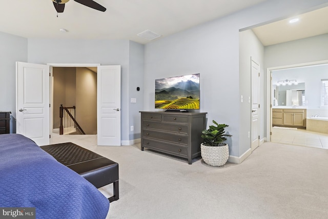 bedroom with ensuite bathroom, light carpet, and ceiling fan