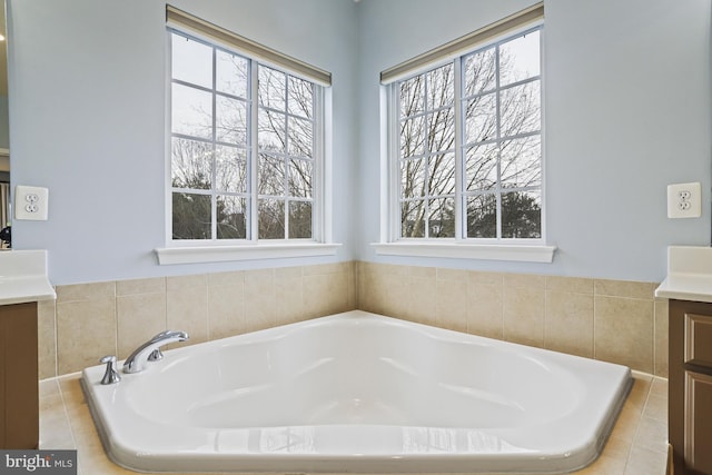 bathroom featuring a relaxing tiled tub and vanity