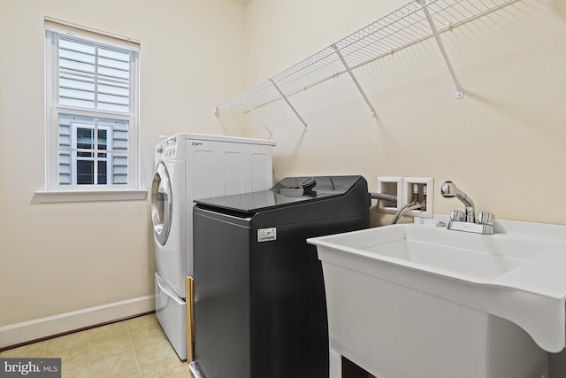 laundry room with washing machine and dryer, sink, and light tile patterned flooring