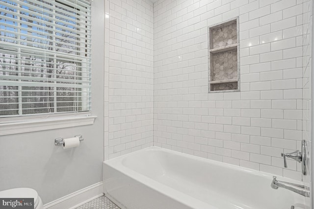 bathroom with tile patterned flooring, tiled shower / bath combo, and toilet