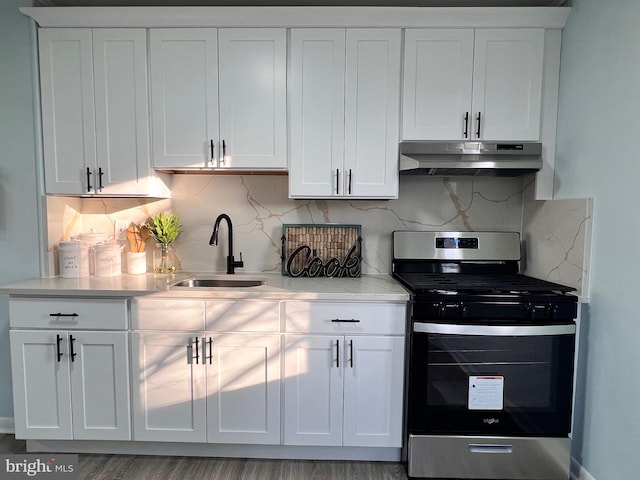 kitchen featuring stainless steel gas stove, sink, decorative backsplash, and white cabinetry