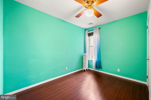 spare room featuring dark hardwood / wood-style flooring, radiator, and ceiling fan