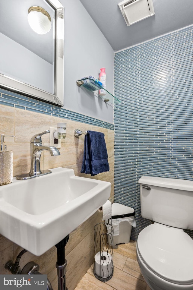 bathroom featuring sink, tile walls, and toilet