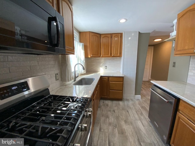 kitchen featuring tasteful backsplash, sink, light hardwood / wood-style flooring, and appliances with stainless steel finishes