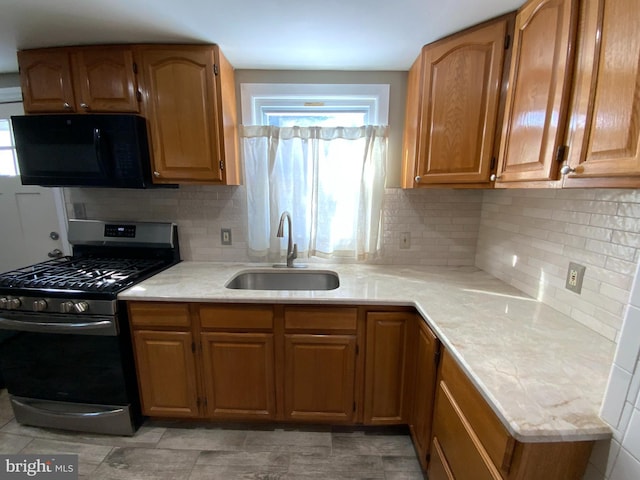 kitchen with stainless steel gas stove, sink, and decorative backsplash