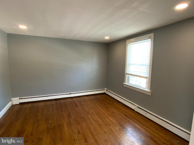 spare room featuring hardwood / wood-style flooring and a baseboard heating unit