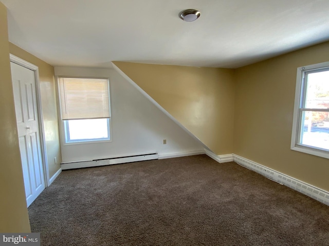 bonus room with a baseboard radiator and dark colored carpet