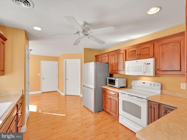 kitchen with ceiling fan, sink, white appliances, and light hardwood / wood-style floors