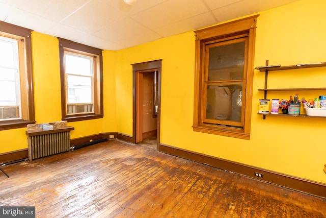 unfurnished room featuring radiator, a paneled ceiling, and dark hardwood / wood-style floors