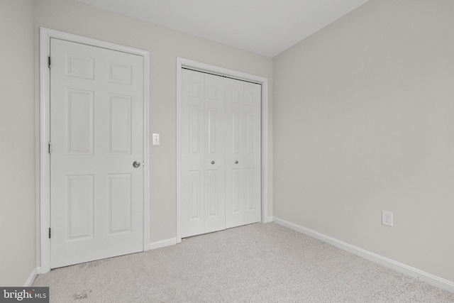 unfurnished bedroom with light colored carpet and a closet