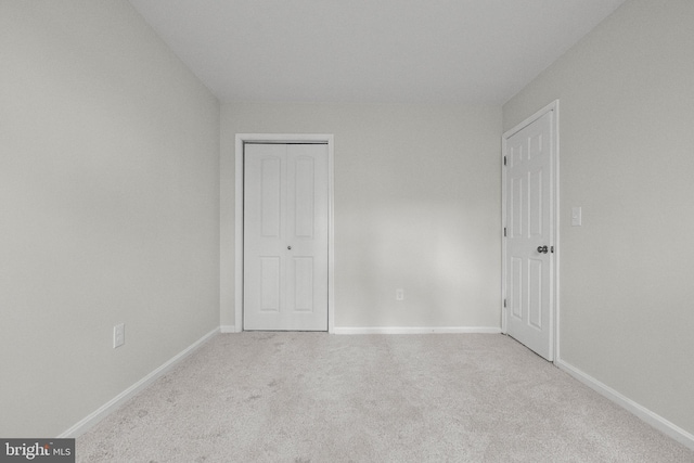 unfurnished bedroom with light colored carpet and a closet