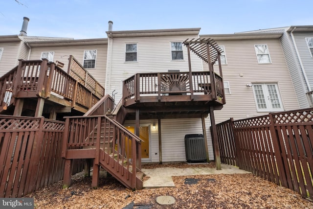 back of property with a wooden deck, a pergola, and central AC