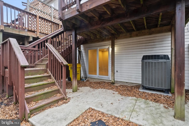 doorway to property with a wooden deck, central AC unit, and a patio