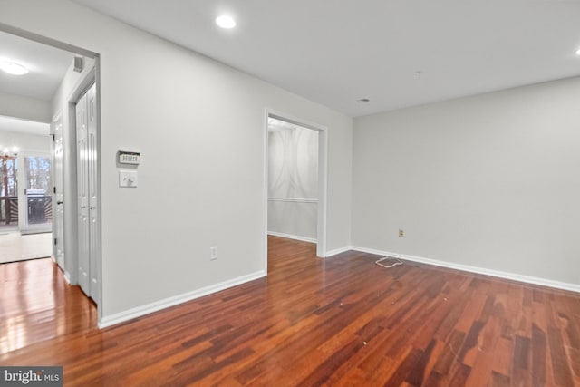 empty room featuring an inviting chandelier and dark hardwood / wood-style floors