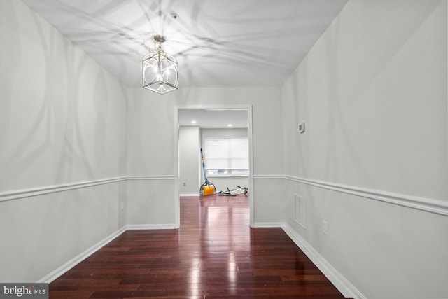 hall with dark wood-type flooring and an inviting chandelier