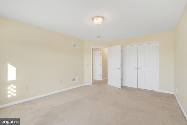 unfurnished bedroom featuring light carpet and a closet