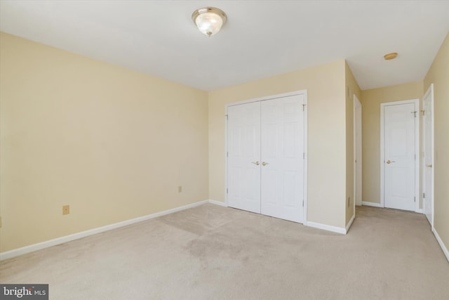 unfurnished bedroom with light colored carpet and a closet