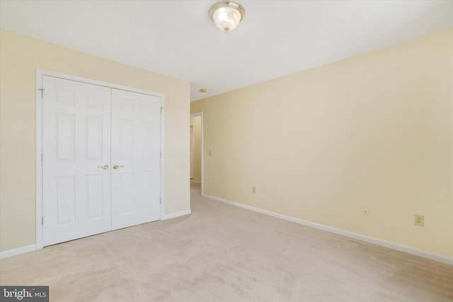 unfurnished bedroom featuring light colored carpet and a closet