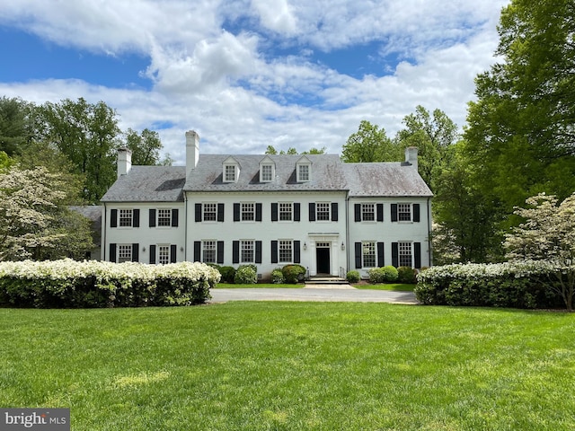 view of front facade featuring a chimney and a front lawn