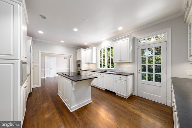 kitchen featuring dark countertops, white cabinetry, decorative backsplash, and a sink