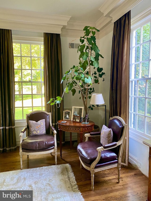 sitting room with ornamental molding and wood finished floors