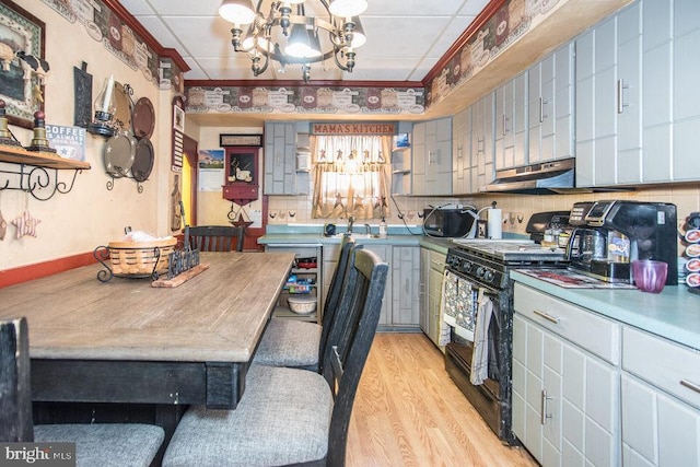 kitchen with ornamental molding, black range with gas stovetop, an inviting chandelier, and light hardwood / wood-style flooring