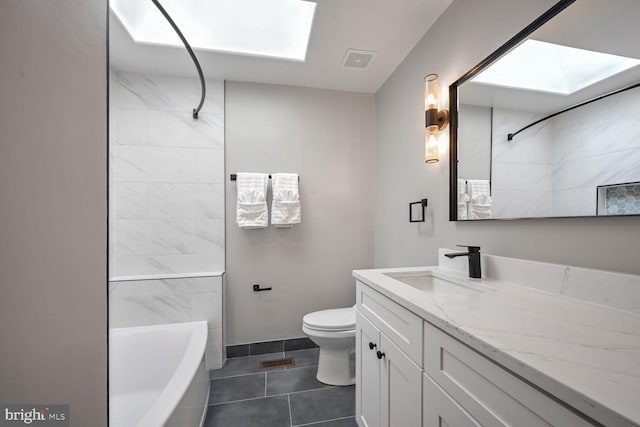 full bathroom featuring vanity, a skylight, tiled shower / bath combo, toilet, and tile patterned floors