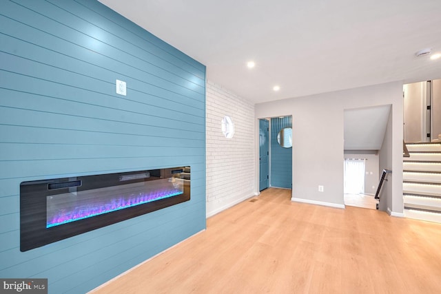 living room with light hardwood / wood-style floors and brick wall