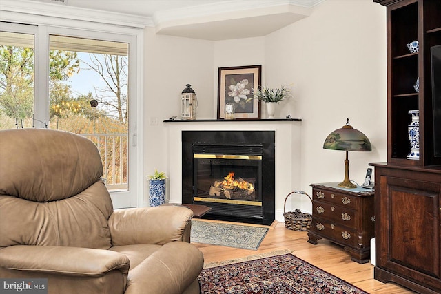 sitting room with ornamental molding and light wood-type flooring