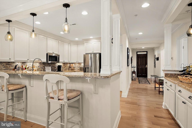 kitchen featuring white cabinetry, light stone countertops, appliances with stainless steel finishes, and pendant lighting