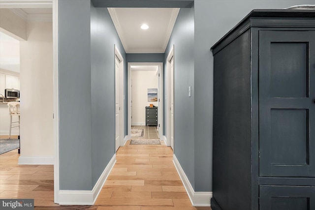 hallway featuring ornamental molding and light hardwood / wood-style flooring