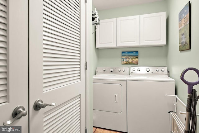 clothes washing area with cabinets and separate washer and dryer