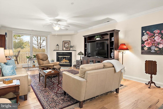 living room featuring crown molding, a high end fireplace, ceiling fan, and light wood-type flooring