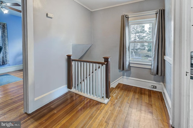 stairway featuring crown molding, ceiling fan, and wood-type flooring